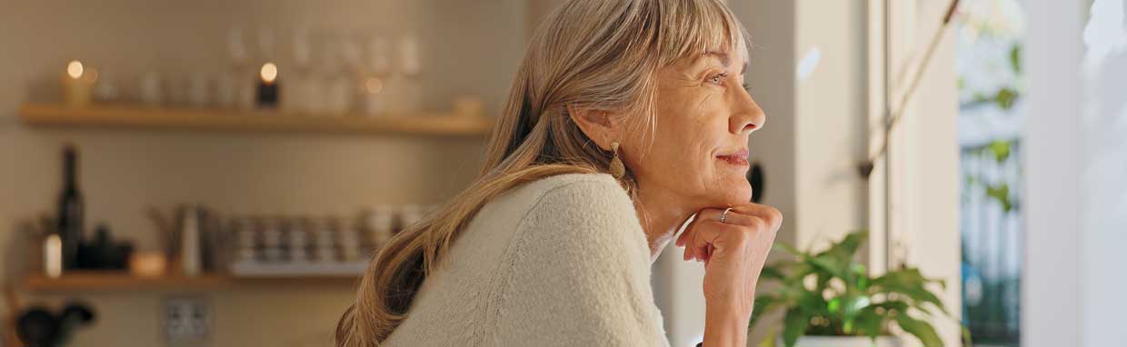 mature lady looking out of her kitchen window with a smile