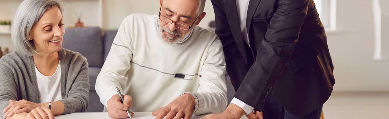 mature couple signing documents with an advisor